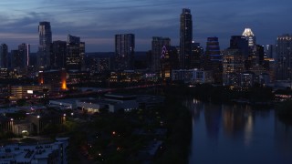 DX0002_110_049 - 5.7K aerial stock footage descend by Lady Bird Lake, focus on skyline at twilight in Downtown Austin, Texas