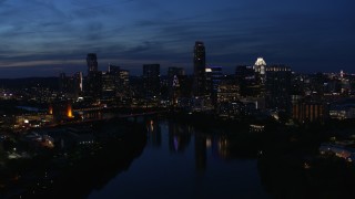 DX0002_111_001 - 5.7K aerial stock footage ascend over Lady Bird Lake, focus on the waterfront skyline at twilight in Downtown Austin, Texas