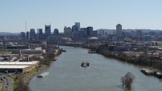 DX0002_112_021 - 5.7K aerial stock footage a barge sailing the river toward the city's skyline, Downtown Nashville, Tennessee