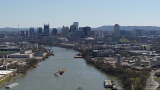 DX0002_112_022 - 5.7K aerial stock footage flying by barge sailing the river toward the city's skyline, Downtown Nashville, Tennessee