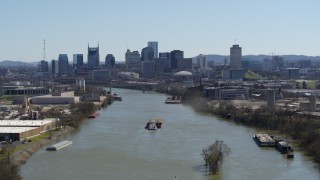 DX0002_112_023 - 5.7K aerial stock footage passing by barge on the river toward the city's skyline, Downtown Nashville, Tennessee