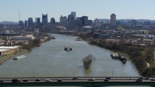 DX0002_112_025 - 5.7K aerial stock footage a barge on the river, sailing toward the city's skyline, seen from a bridge, Downtown Nashville, Tennessee