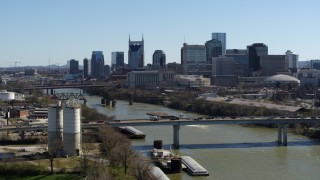 DX0002_113_006 - 5.7K aerial stock footage focus on city skyline while passing traffic on bridge over the river, Downtown Nashville, Tennessee