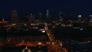 DX0002_115_052 - 5.7K aerial stock footage fly away from the city skyline at night, reveal flashing lights on Church Street, Downtown Nashville, Tennessee