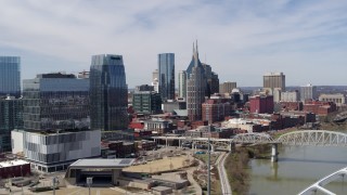 DX0002_116_003 - 5.7K aerial stock footage flying past skyscrapers near a bridge spanning the river in Downtown Nashville, Tennessee