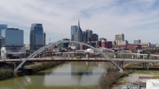 DX0002_116_005 - 5.7K aerial stock footage reverse and then stationary view of skyscrapers seen from a bridge spanning the river in Downtown Nashville, Tennessee