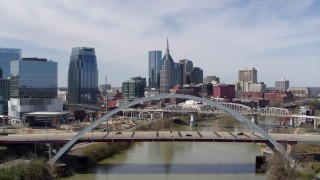 DX0002_116_008 - 5.7K aerial stock footage descend near a bridge over the river with view of skyscrapers in Downtown Nashville, Tennessee