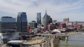 DX0002_116_012 - 5.7K aerial stock footage of flying by skyscrapers and reveal a bridge over the river in Downtown Nashville, Tennessee