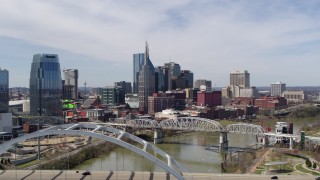 DX0002_116_013 - 5.7K aerial stock footage of ascend from bridge to focus on skyscrapers across the river in Downtown Nashville, Tennessee