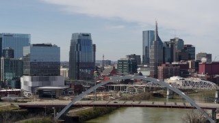 DX0002_116_028 - 5.7K aerial stock footage fly away from river and bridge, office high-rise and skyscrapers in Downtown Nashville, Tennessee
