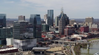 DX0002_116_030 - 5.7K aerial stock footage flyby Cumberland River and bridge, closer view of office high-rise and skyscrapers in Downtown Nashville, Tennessee