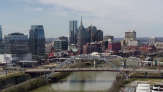 DX0002_116_039 - 5.7K aerial stock footage pass a bridge and the river while focused on city skyscrapers in Downtown Nashville, Tennessee