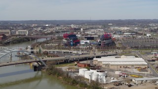 DX0002_116_043 - 5.7K aerial stock footage wide orbit of Nissan Stadium near bridge, seen from Cumberland River in Nashville, Tennessee