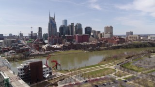 DX0002_117_010 - 5.7K aerial stock footage orbit city's riverfront skyscrapers across the Cumberland River near the pedestrian bridge, Downtown Nashville, Tennessee