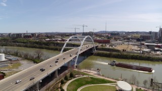 DX0002_117_014 - 5.7K aerial stock footage of a barge sailing away from a bridge in Nashville, Tennessee