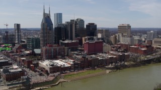 DX0002_117_021 - 5.7K aerial stock footage the city's skyline overlooking the Cumberland River, descend near pedestrian bridge, Downtown Nashville, Tennessee