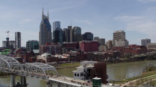 DX0002_117_024 - 5.7K aerial stock footage ascend by pedestrian bridge, focus on city's skyline, Downtown Nashville, Tennessee