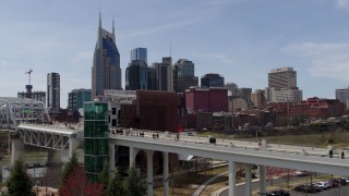 DX0002_117_026 - 5.7K aerial stock footage ascend by pedestrian bridge with view of city's skyline, Downtown Nashville, Tennessee