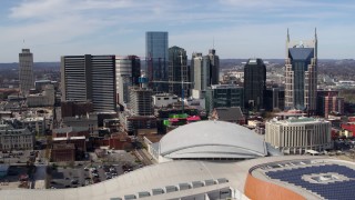 DX0002_117_036 - 5.7K aerial stock footage of flying by the city's skyline behind the arena and hotel, Downtown Nashville, Tennessee