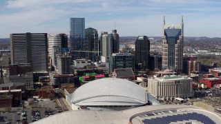 DX0002_117_045 - 5.7K aerial stock footage of passing the city's skyline, seen behind the arena and hotel, Downtown Nashville, Tennessee