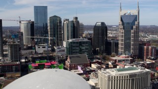 DX0002_117_048 - 5.7K aerial stock footage of flying away from the city's skyline, Bridgestone Arena, and Hilton hotel, Downtown Nashville, Tennessee