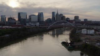 DX0002_119_034 - 5.7K aerial stock footage follow the river toward the bridge and city skyline at sunset, Downtown Nashville, Tennessee