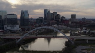 DX0002_119_043 - 5.7K aerial stock footage flying by the city skyline near bridges and Cumberland River at sunset, Downtown Nashville, Tennessee