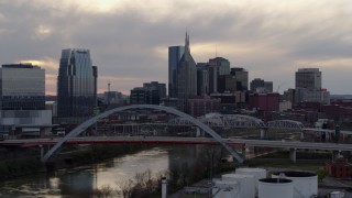 DX0002_120_002 - 5.7K aerial stock footage city skyline seen while flying by bridge on Cumberland River at sunset, Downtown Nashville, Tennessee