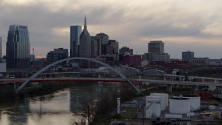 DX0002_120_004 - 5.7K aerial stock footage flying by riverfront skyline, bridge, and Cumberland River at sunset, Downtown Nashville, Tennessee