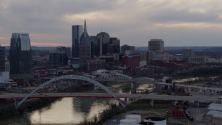 DX0002_120_007 - 5.7K aerial stock footage flying away from riverfront skyline, bridges, and the Cumberland River at sunset, Downtown Nashville, Tennessee