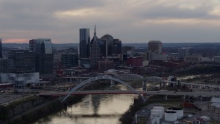 DX0002_120_008 - 5.7K aerial stock footage flying by the riverfront skyline and bridges spanning the Cumberland River at sunset, Downtown Nashville, Tennessee