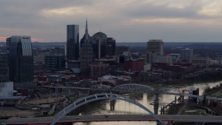 DX0002_120_009 - 5.7K aerial stock footage passing by the riverfront skyline and bridges spanning the Cumberland River at sunset, Downtown Nashville, Tennessee
