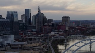 DX0002_120_010 - 5.7K aerial stock footage of the AT&T Building and neighboring buildings by the Cumberland River at sunset, Downtown Nashville, Tennessee