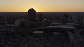 DX0002_122_049 - 5.7K aerial stock footage ascend to reveal sunset behind office tower and shorter hotel tower, Downtown Albuquerque, New Mexico