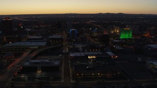DX0002_123_027 - 5.7K aerial stock footage wide orbit of hotel with blue lighting near office buildings at twilight, Downtown Albuquerque, New Mexico