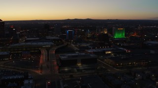 DX0002_123_029 - 5.7K aerial stock footage of the DoubleTree hotel with blue lighting near office buildings at twilight, Downtown Albuquerque, New Mexico