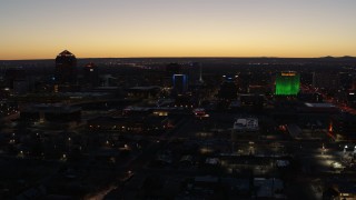 DX0002_123_031 - 5.7K aerial stock footage flyby and approach DoubleTree hotel with blue lighting near office buildings at twilight, Downtown Albuquerque, New Mexico