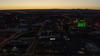 DX0002_123_032 - 5.7K stock footage aerial video ascend and orbit DoubleTree hotel with blue lighting near office buildings at twilight, Downtown Albuquerque, New Mexico