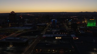 DX0002_123_033 - 5.7K aerial stock footage fly past hotel with blue lighting near office towers at twilight, Downtown Albuquerque, New Mexico
