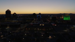 DX0002_123_034 - 5.7K aerial stock footage descend past hotel with blue lighting near office towers at twilight, Downtown Albuquerque, New Mexico