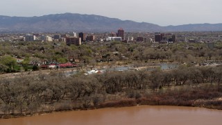 DX0002_124_004 - 5.7K aerial stock footage wide view of high-rise office buildings, descend beside park, Rio Grande, Downtown Albuquerque, New Mexico