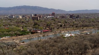DX0002_124_008 - 5.7K aerial stock footage flying by park and Rio Grande with view of high-rise office buildings, Downtown Albuquerque, New Mexico