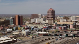 DX0002_124_021 - 5.7K aerial stock footage of an office high-rise seen while ascending near train tracks, Downtown Albuquerque, New Mexico