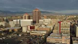 DX0002_127_031 - 5.7K aerial stock footage wide orbit of Albuquerque Plaza high-rise towering over city buildings, Downtown Albuquerque, New Mexico