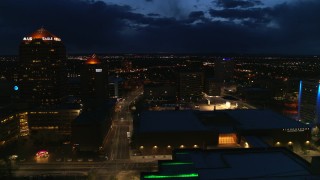 DX0002_128_040 - 5.7K aerial stock footage follow street between high-rise hotel and auditorium at twilight, Downtown Albuquerque, New Mexico