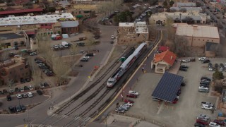 DX0002_130_021 - 5.7K aerial stock footage fly away from bird's eye of a passenger train at a station in Santa Fe, New Mexico, tilt to top of the train
