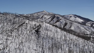 DX0002_134_028 - 5.7K aerial stock footage of a reverse view of a snowy mountain slope with dead trees, New Mexico