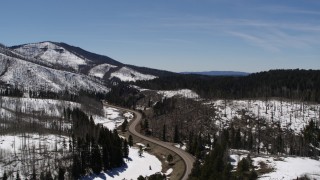 DX0002_134_029 - 5.7K aerial stock footage of following a winding road by snowy mountains, New Mexico
