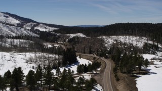 DX0002_134_035 - 5.7K aerial stock footage flyby black car on winding road by snowy mountains, New Mexico