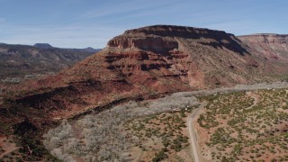 DX0002_135_003 - 5.7K aerial stock footage of orbiting a butte beside a road, New Mexico